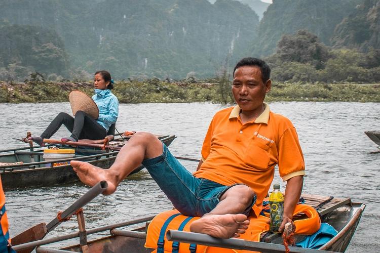 Tam Coc, Ninh Binh boat tour. Vietnamese man rowing the boat with his feet