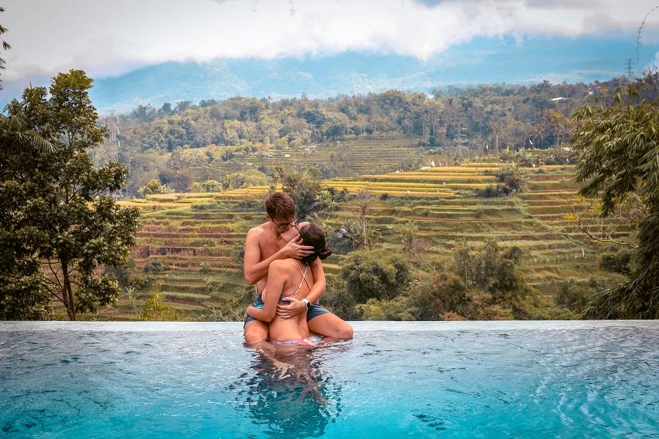 Couple on the edge of an infinity pool overlooking the rice fields in Bali