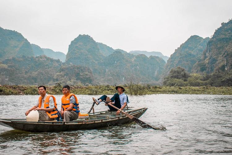 Vietnamese man rowing the boat with his feet in Ninh Binh, Vietnam